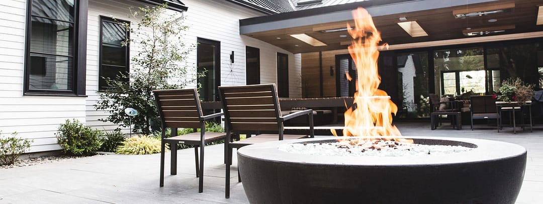 Outdoor living area with firepit in foreground and table and chairs in background